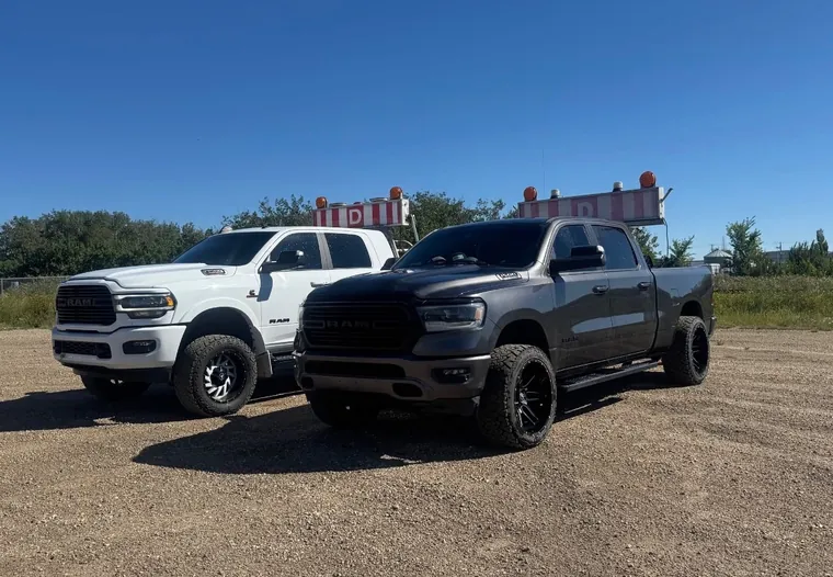 Two pilot trucks parked up on a gravel pad